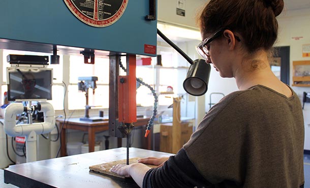Torre Viola, a sophomore in electrical engineering, utilizes an electric band saw with real-time feedback provided by the co-robot system called "Pennie," that she helped design and assemble from off-the-shelf parts.