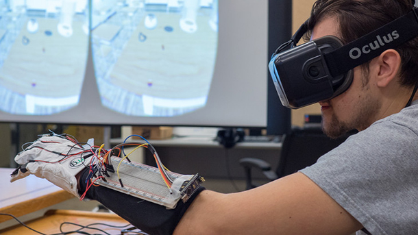 In two worlds at once: Engineering student Owen Shartle explores a virtual scene with the aid of a headset and a haptic glove he and other undergraduates helped design. 