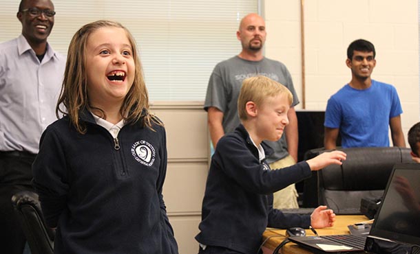 Second-grader Mary Patrick reacts to her twin brother Patrick's attempts to place the head of a robot back on its body using motion-detection software. 