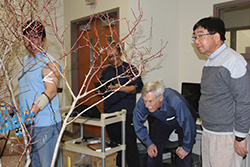 Kim uses one of the shakers on the blueberry bush while fellow graduate student Kiseok Sung records the force the shaker has on Kim’s muscles as Andris Frievalds and Fumioni Takeda observe the test.