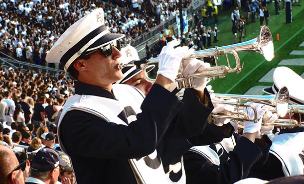 Zuber playing the trumpet with the Blue Band in the stands of Beaver Stadium during one of the football team's home games.
