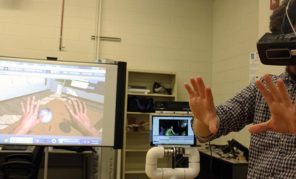 Owen Shartle (senior, computer science and engineering) views a digital version of his hands in the immersive virtual reality classroom environment designed in the Design Analysis Technology Advancement (DATA) Lab.